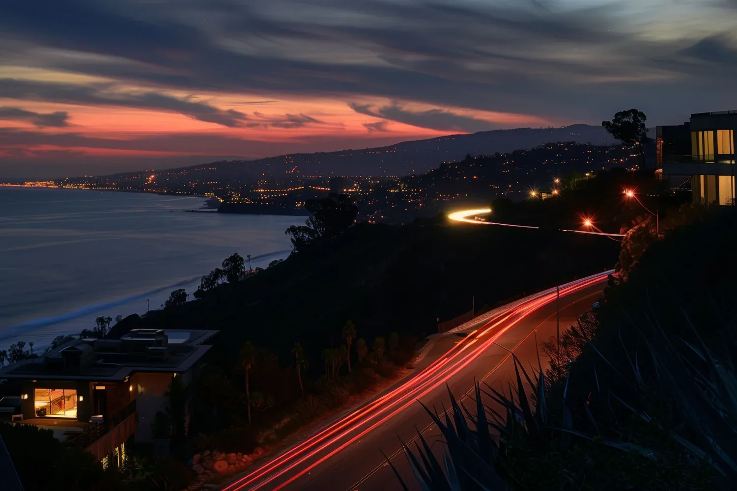 Pacific Palisades coastline at sunset with car light trails and city lights
